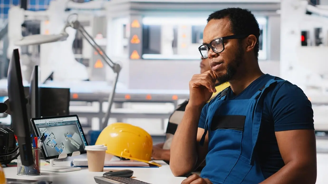 Schwarzer Ingenieur führt Diagnosetests an der Montagesoftware für Solarmodule zur Optimierung der Produktion durch.